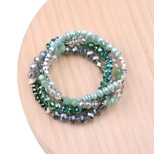 Dettaglio di bracciali con perle di cristallo verde su un espositore in legno naturale