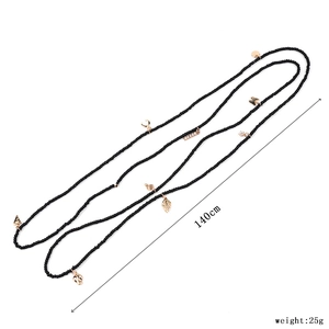 Detailed macro view of 140cm long black Miyuki bead necklace with various gold charms