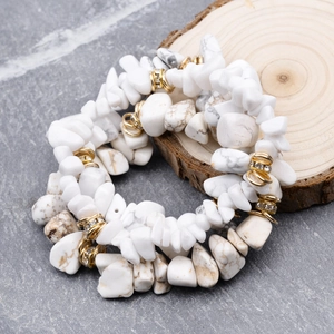 Natural irregular white turquoise stone bracelets with gold spacers on stone background