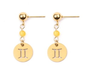 Détail de boucles d'oreilles Gémeaux en finition dorée avec perle œil de chat jaune