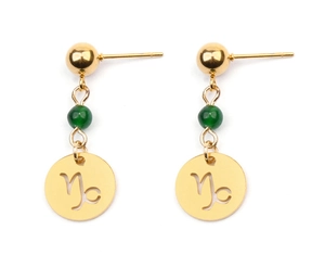Détail de boucle d'oreille Capricorne avec pendentif doré et perle verte sur fond blanc