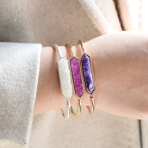 Tre bracciali rigidi in pietra druzy oro, argento e oro rosa indossati sul polso