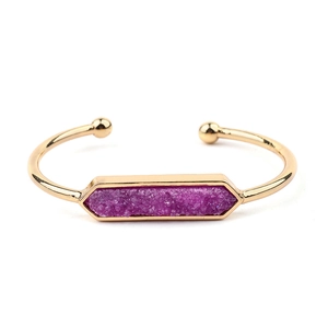 Dettaglio di un bracciale a polsino dorato con intarsio in pietra naturale druzy viola esagonale