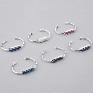 Dettaglio di pietre druzy esagonali incastonate su bracciali aperti in metallo lucido