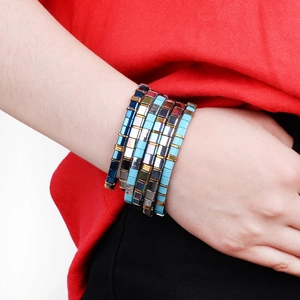 Close-up of colorful Tila bead stretch bracelets featuring a bohemian layered design