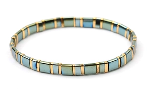 Macro detail of elastic tila bead bracelet with iridescent blue and gold metallic tiles