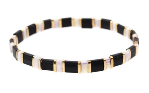 Macro view of Tila tile bracelet featuring black white and gold beads on elastic cord