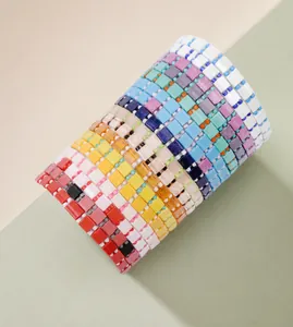 Macro detail of colorful Tila bead woven bracelets on white cylinder display