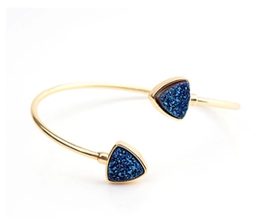 Detalle del brazalete abierto dorado con incrustaciones de cristales azules triangulares