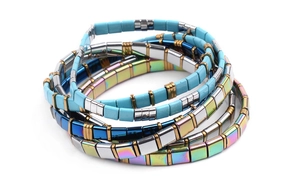 Close-up of stacked colorful Tila bead bracelets with gold metallic spacers and elastic band