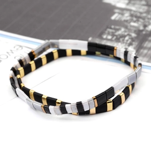 Detail of square Tila bead bracelet with gold, black, and white minimalist tiling