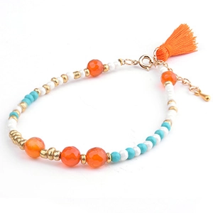 Detail of bohemian beaded bracelet featuring orange tassels and turquoise stones