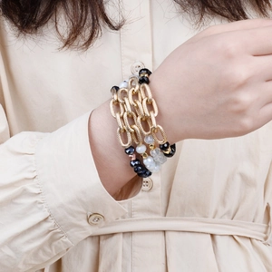 Detail of layered gold chain bracelet with black and clear faceted crystal beads for women