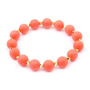 Detailopname van gefacetteerde koraaloranje kralenarmband met gouden geometrische kralen