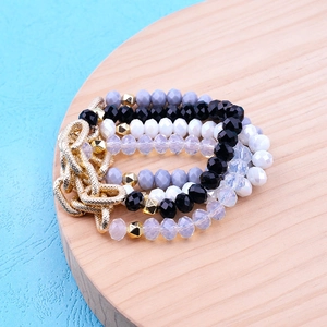 Multilayer faceted bead bracelet with golden chain links on a round wooden display
