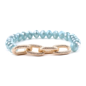 Detail of faceted light blue crystal beads and gold textured metal links on a bracelet