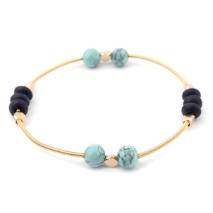 Detail view of gold coiled bracelet with blue turquoise beads and navy wood accents