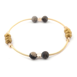 Detailed close-up of golden spring beads and natural stone beads on a stretch bracelet