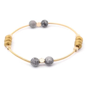 Detail of golden coil spring bracelet with grey stone beads and metallic spacers