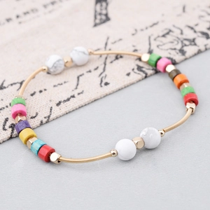 Primer plano de cuentas de madera coloridas y mármol blanco en brazalete de espiral dorado