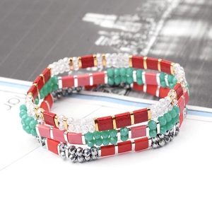 Detail of layered bohemian Miyuki bead bracelets with red, pink and mint beads