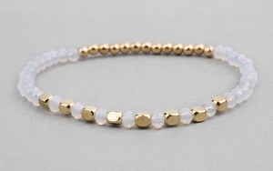 Close-up of handmade beaded bracelet with white crystals and gold geometric beads.