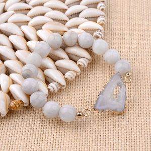 Détail d'un bracelet en pierres naturelles avec tranche d'agate sur des coquillages