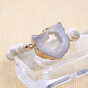 Détail d'une tranche de géode naturelle dorée sur un bracelet en perles de style bohème