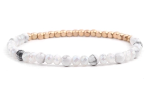 Dettaglio di bracciale con perline dorate e trame in pietra di marmo bianco