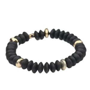 Close-up of black matte disk beads with textured gold metal accents on elastic bracelet