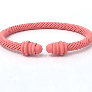 Macro shot of coral pink twisted cable cuff bracelet with matte finish and rounded ends