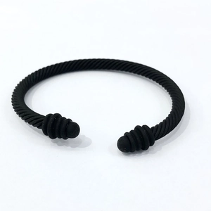Detailed close-up of a matte black cable wire twisted cuff bracelet with sphere finials