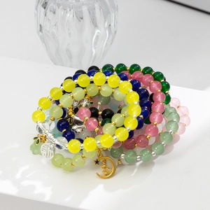 Dettaglio di braccialetti con perline colorate, ciondolo Fu d'argento e coniglio dorato