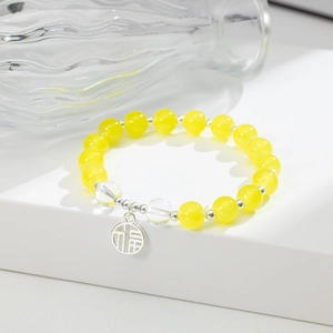 Dettaglio del bracciale con perline di cristallo giallo e ciondolo in argento simbolo Fu