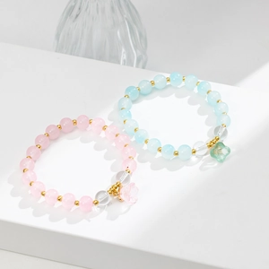 Dettaglio di braccialetti con perline mughetto rosa e blu e distanziatori dorati