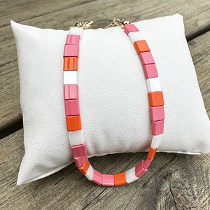 Close-up of pink, orange and white Tila beads with golden lobster clasp and chain