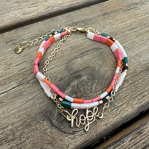 Detail of multi-layer boho Tila bead bracelet with a golden 'hope' letter pendant charm