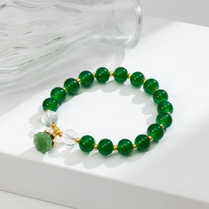 Dettaglio di perle verde scuro con ciondolo a fiore di loto intagliato e accenti dorati