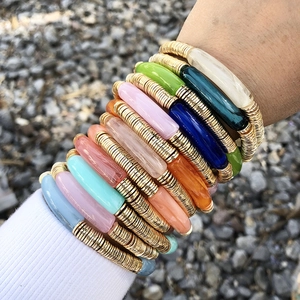 Détail de bracelets en perles acryliques colorées avec disques dorés portés au poignet