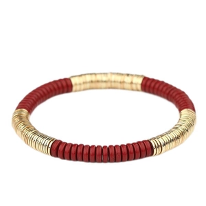 Vista macro de pulsera bohemia con cuentas Heishi rojas y doradas en forma de disco