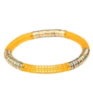 Detalle de discos acrílicos amarillos y placas de metal dorado en la pulsera elástica