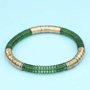 Detalle de una pulsera boho de acrílico con cuentas verdes planas y aros metálicos dorados