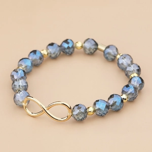 Gedetailleerde close-up van de donkerblauwe kristallen kralen en gouden infinity-bedel armband