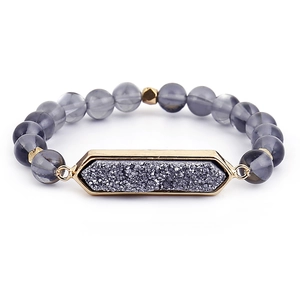 Détail d'un bracelet en perles violettes avec un pendentif en pierre druzy gris foncé