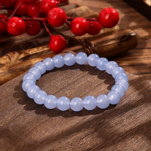 Detail of light blue crystal beads bracelet with a smooth polished texture on dark wood