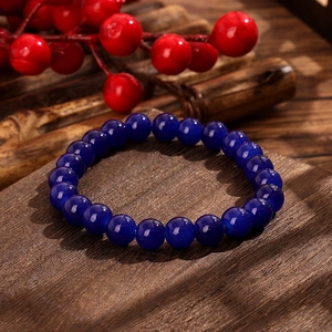 Detailed view of deep blue glass beaded bracelet on a dark rustic wooden background