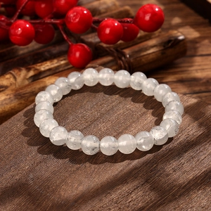 Elegant white translucent beaded crystal bracelet on rustic dark wood with red berries