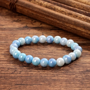 Détail de perles de cristal marbré bleu clair et blanc sur un fond de bois foncé