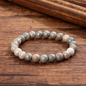 Gros plan d'un bracelet en perles de verre cristal gris avec un éclat naturel sur bois