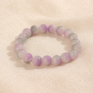 Détail des perles dégradées violettes et grises de 10 mm sur un tissu texturé